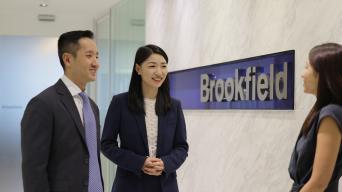Lina Hu talking with colleagues infront of Brookfield signage