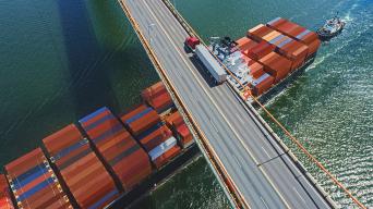 shipping containers passing under a bridge