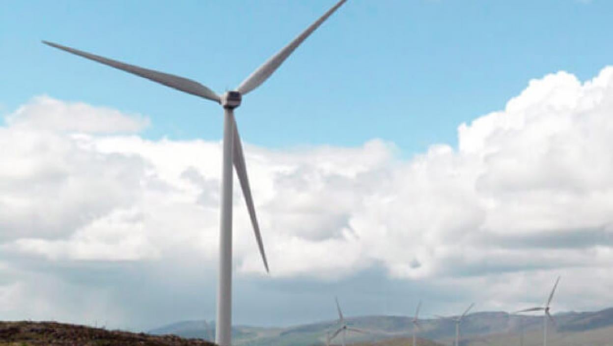 Windmill on hillside; white fluffy clouds in background