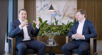 two men sitting in chairs discussing business