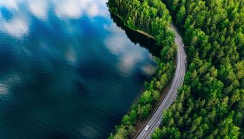 Aerial view of a road winding through a forest and a lake