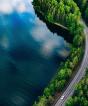 Aerial view of a road winding through a forest and a lake